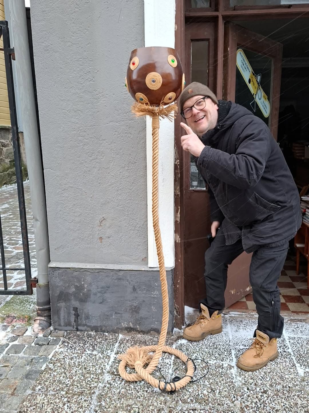 En glad man pekar på en golvlampa av rep och trä